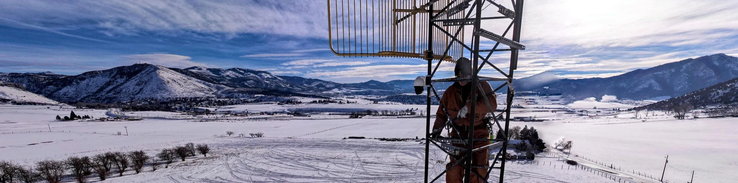 A Lavalink climber working on the tower in winter, snow-covered Lava valley stretching out below